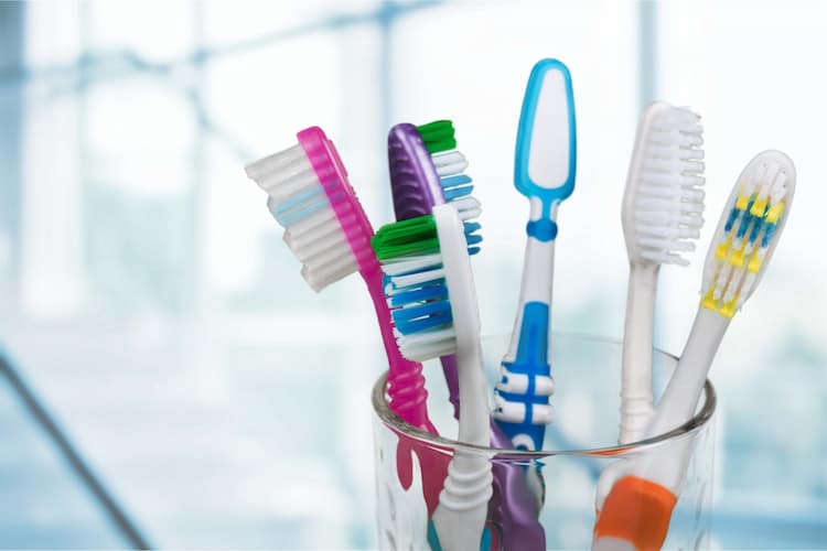 six toothbrushes with different colors in a glass.
