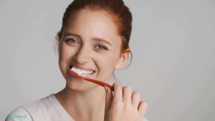 Young woman brushing her teeth as part of aftercare following porcelain veneers treatment.