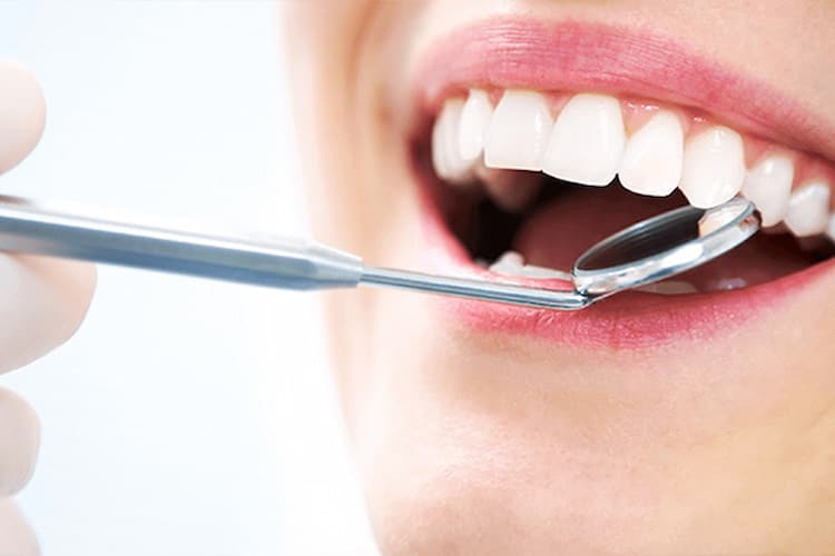 Dental mirror inside open mouth showing bright, healthy white teeth.