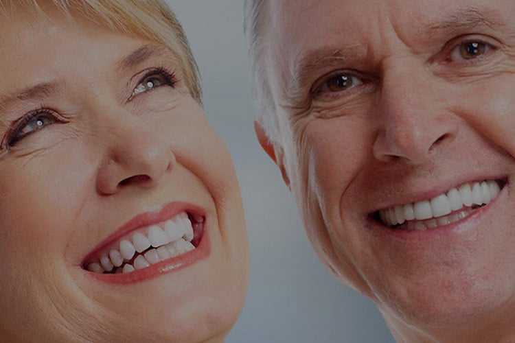 a man and aa woman wearing Custom Dentures and smiling.
