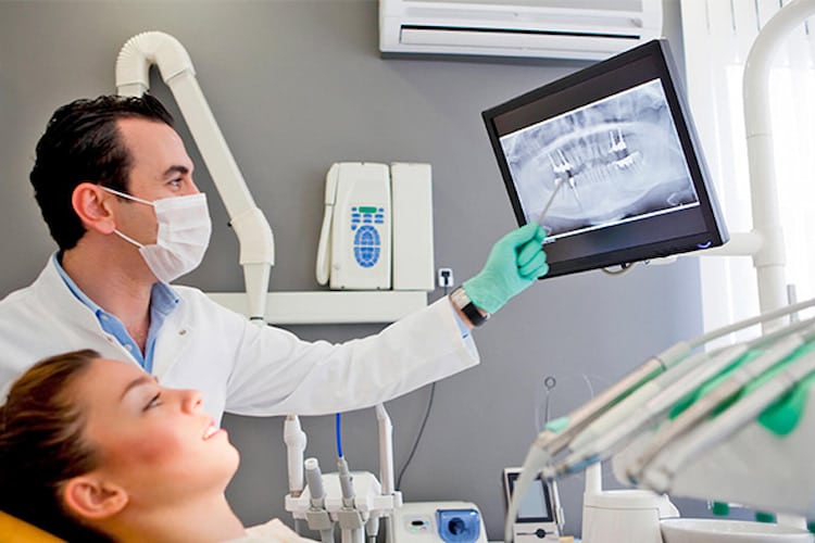 Dentist showing patient their dental X-ray on monitor.
