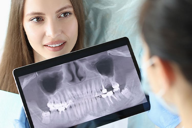 Dentist checking a patient's dental X-ray on monitor and talking to her. 