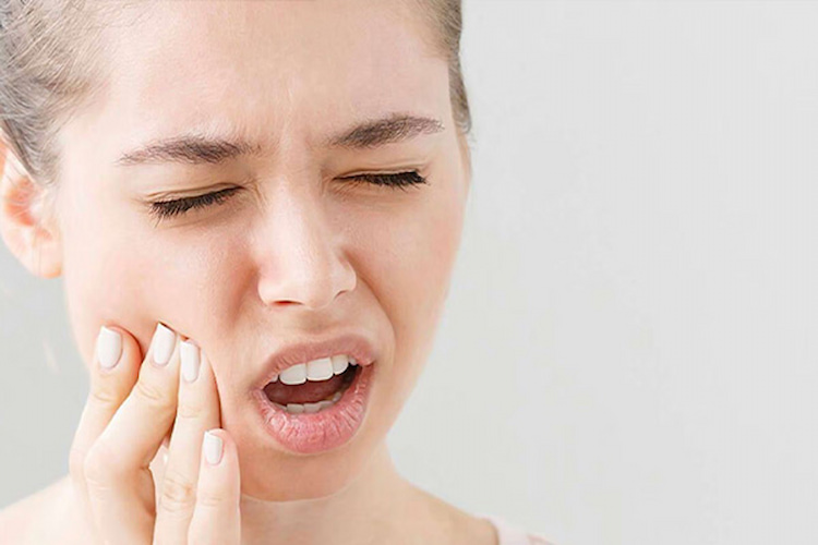 a woman is suffering from severe dental pain