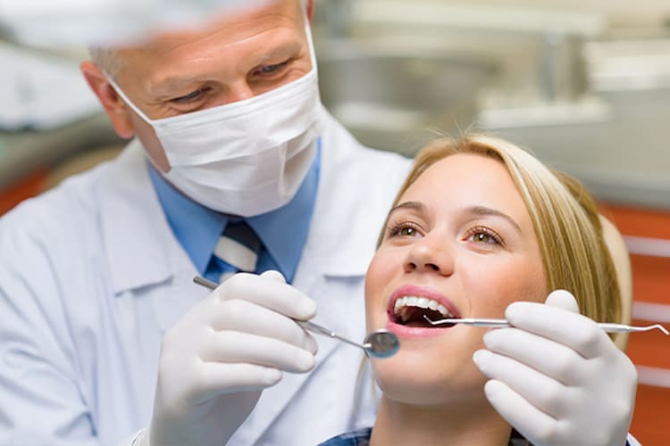 Dentist examining patient's bright smile with mirror and explorer.