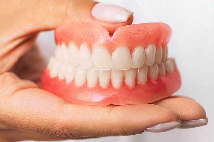 a hand holding a set of dentures.