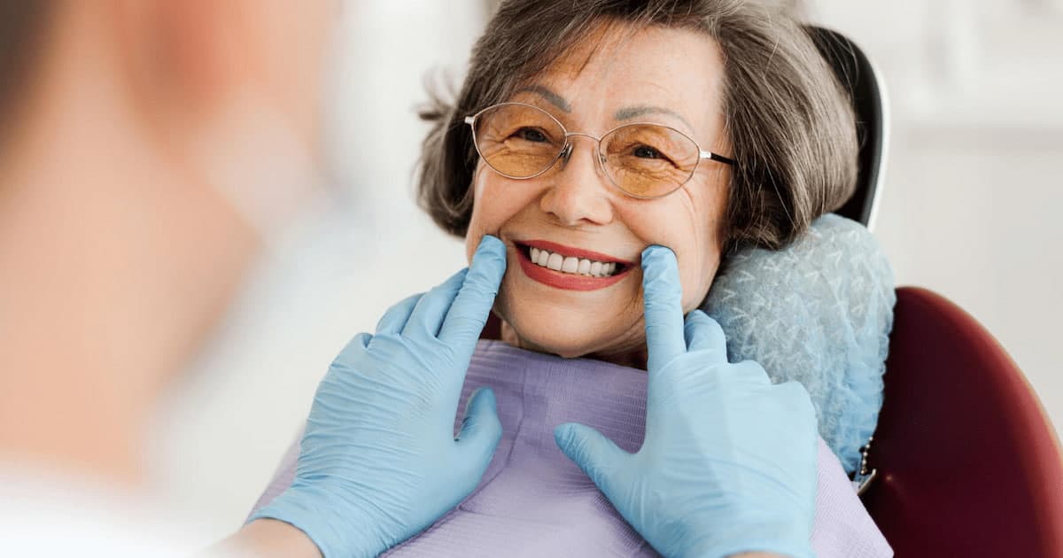 an old woman smiling at her dentist and getting Dental Plan for Seniors in Canada.