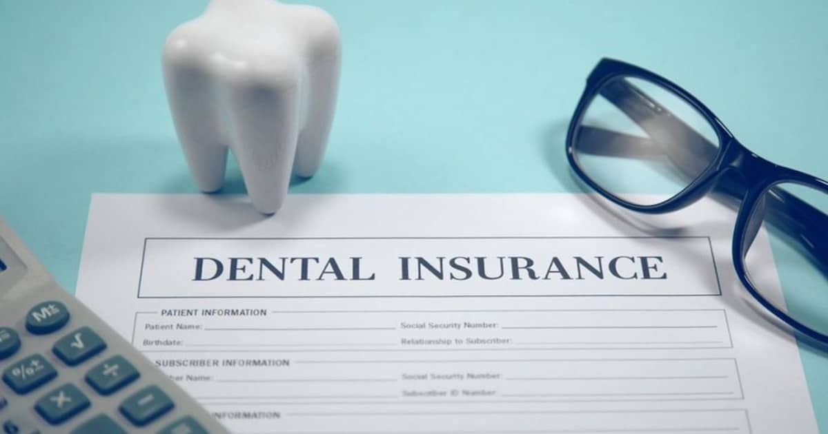 Dental insurance form on a desk with a model tooth, eyeglasses, and calculator beside it, showing best dental insurances in Canada.
