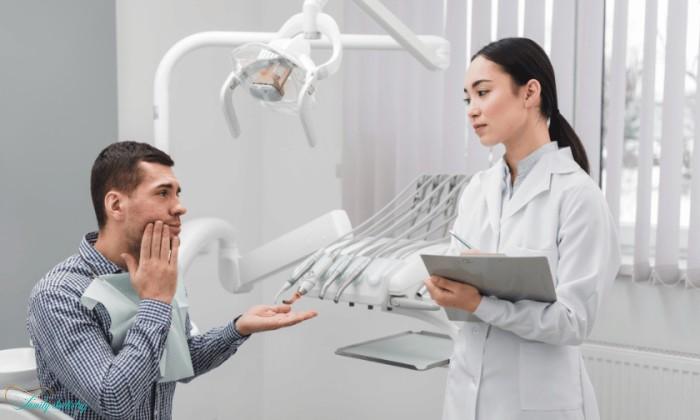 A man visiting a dental office for an emergency dental issue, seeking urgent treatment without dental insurance. A female dentist is listening to him.