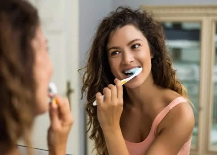 a woman brushing her teeth with a soft toothbrush