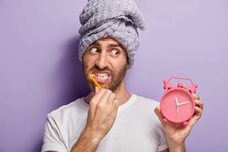 a man cleaning mouth with a clock in his hand